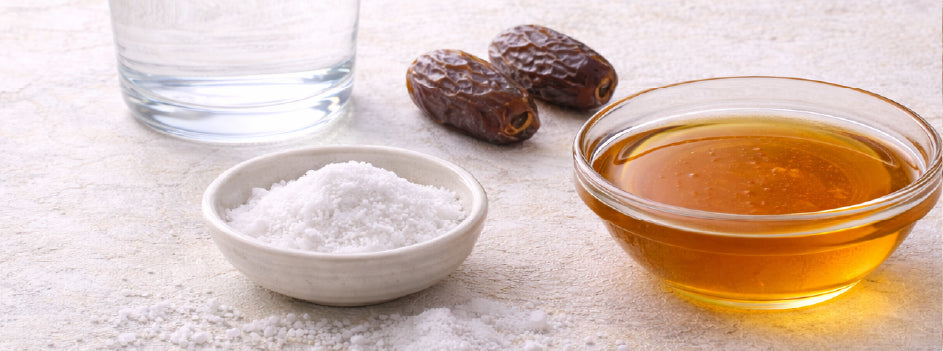 Natural endurance fueling ingredients including honey, dates, sea salt, and water arranged on a light surface.