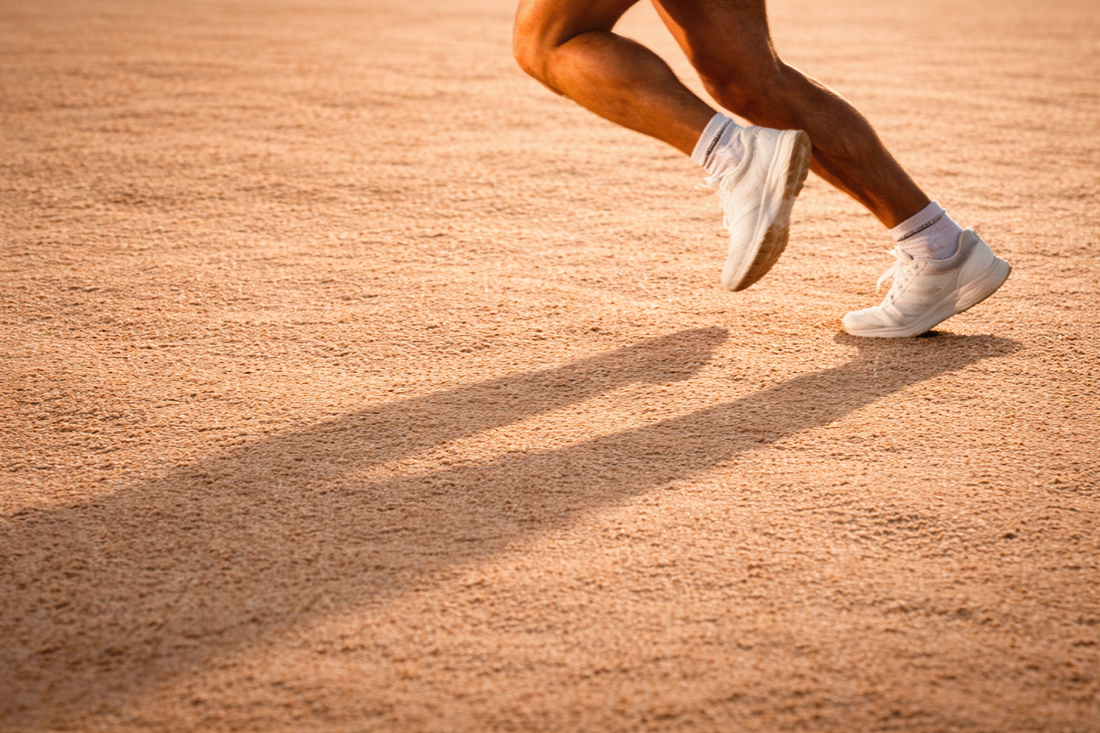 Male legs running on neutral sand background